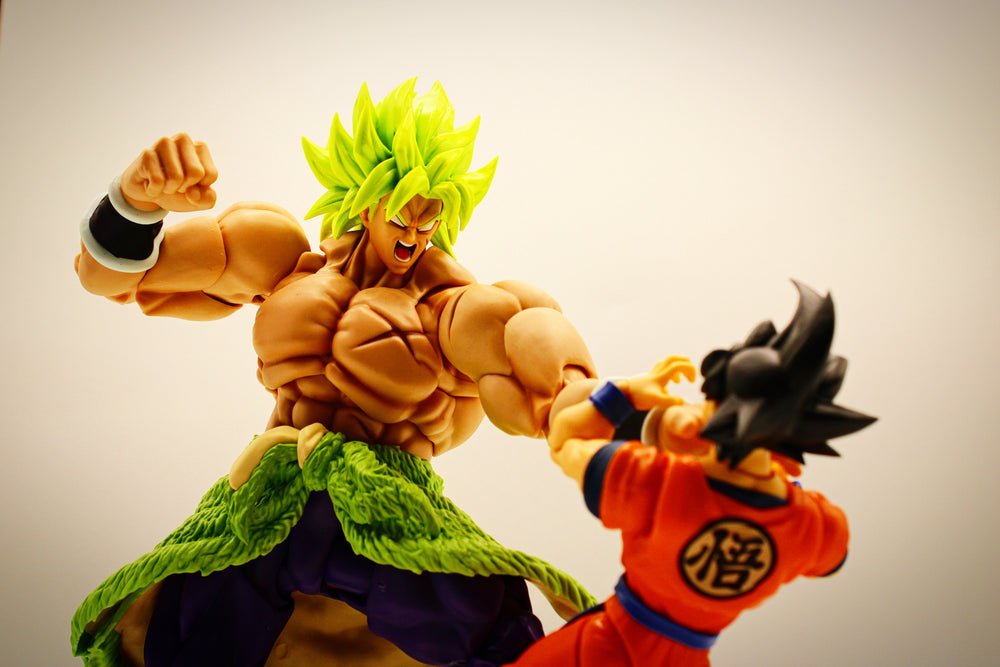Intense battle between Bandai S.H. Figuarts Broly and Goku, with Broly overpowering Goku in a gripping chokehold.