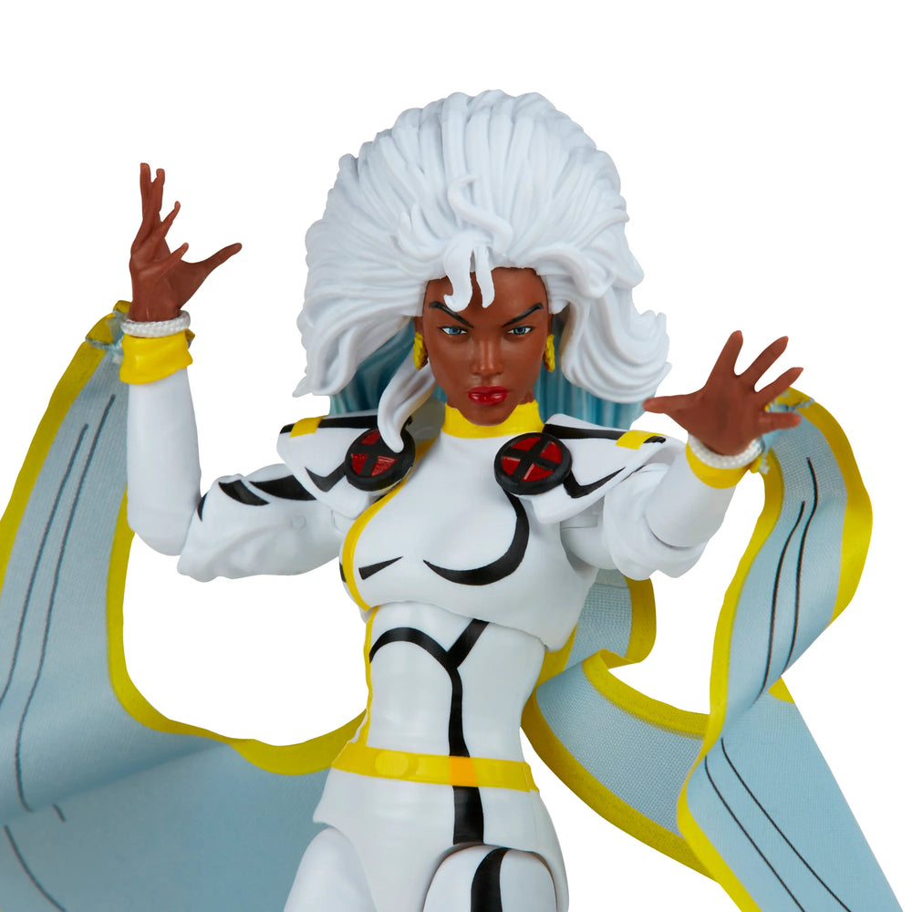 
                  
                    A 6-inch Marvel Legends Series X-Men Storm action figure in a classic white costume, accompanied by alternate hands with crackling electrical energy FX accessories, all contained in a '90s video cassette-inspired packaging.
                  
                