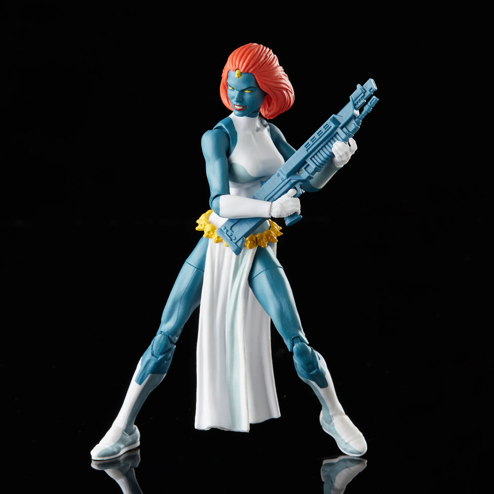 A 6-inch Marvel Legends Series X-Men Marvel's Mystique action figure with blue skin and yellow eyes, featuring accessories such as alternate hands, weapons, and a Baby Nightcrawler figure, all presented in a '90s video cassette-inspired packaging.